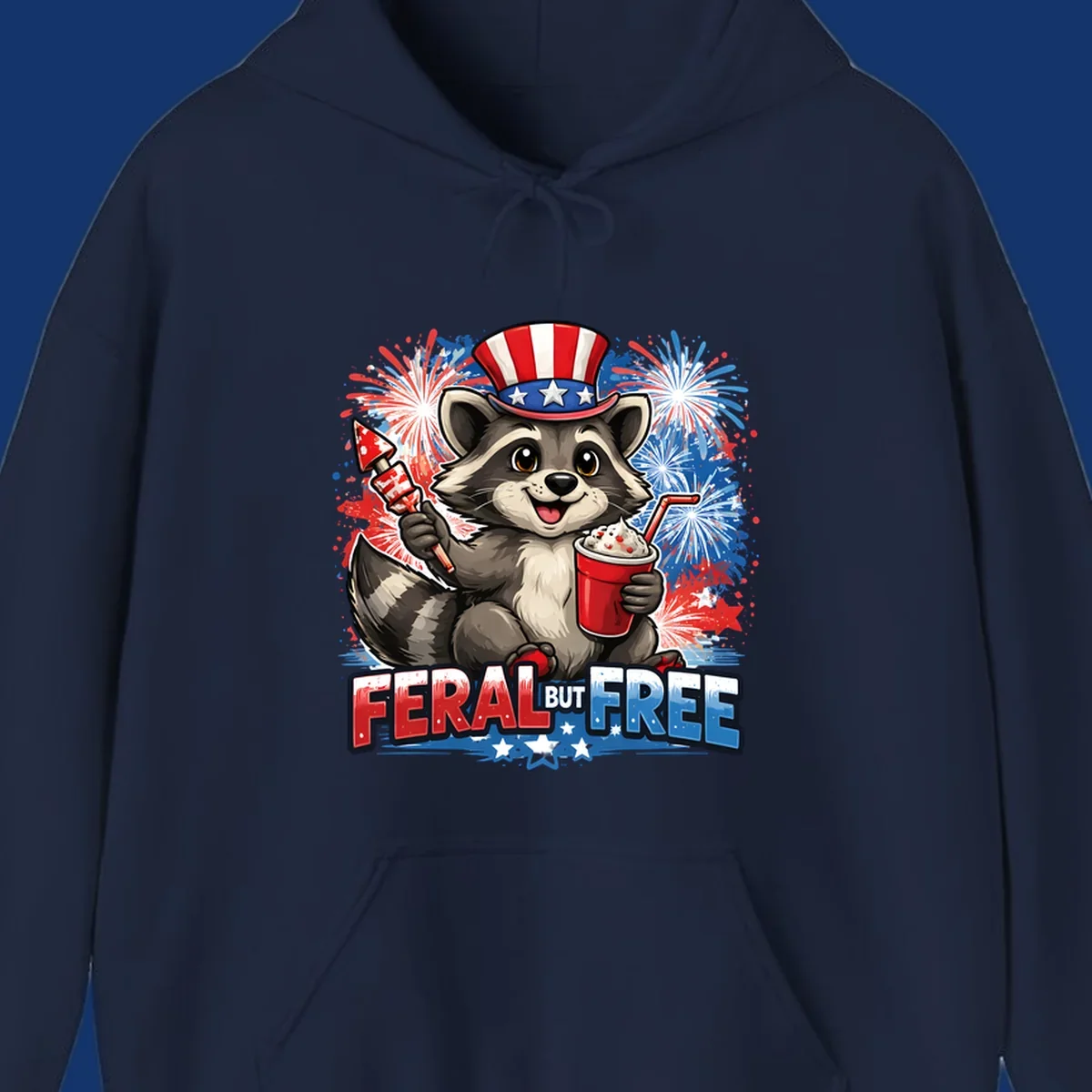A cartoon raccoon in an Uncle Sam hat holds a firework and drink, with red, white, and blue fireworks and "FERAL BUT FREE" text.