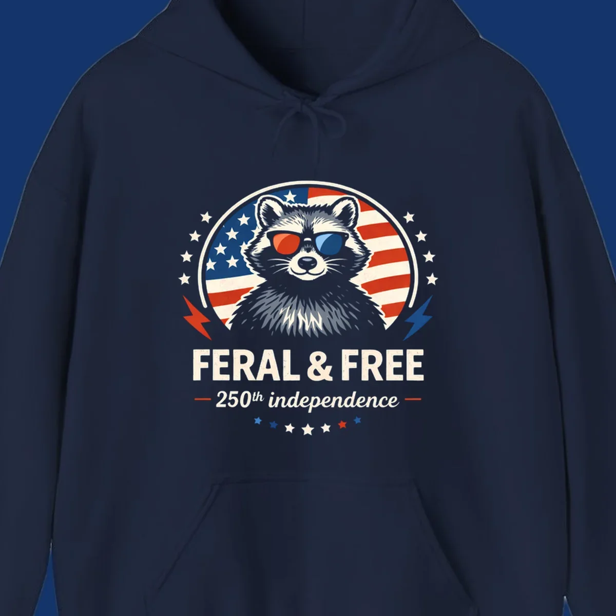 A patriotic design with a raccoon in red and blue sunglasses against an American flag, with text 'Feral & Free 250th Independence'.