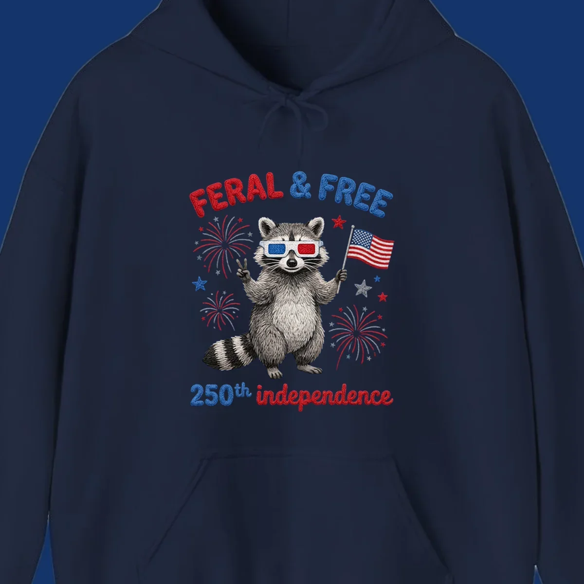 A playful raccoon in 3D glasses holds an American flag, surrounded by fireworks and stars, with "FERAL & FREE 250th independence".