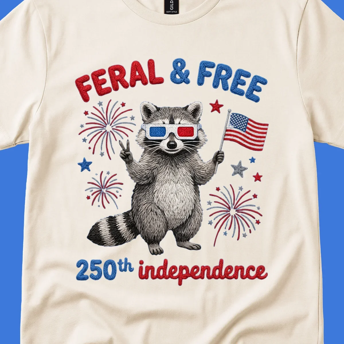 A playful raccoon in 3D glasses holds an American flag, surrounded by fireworks and stars, with "FERAL & FREE 250th independence".