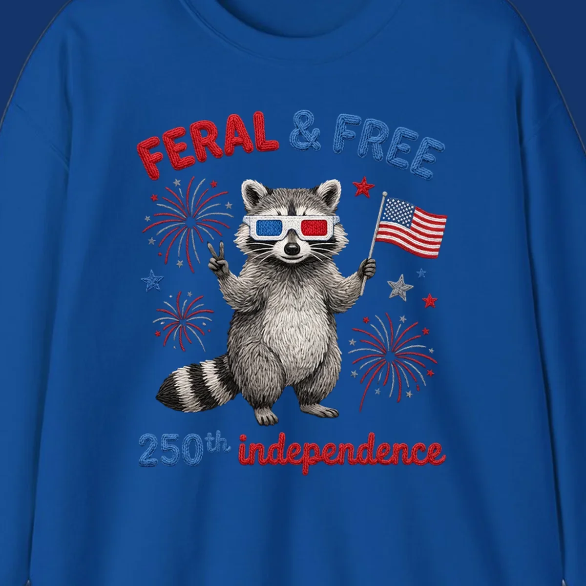 A "FERAL & FREE" raccoon in 3D glasses holds an American flag, surrounded by fireworks, celebrating 250th independence.