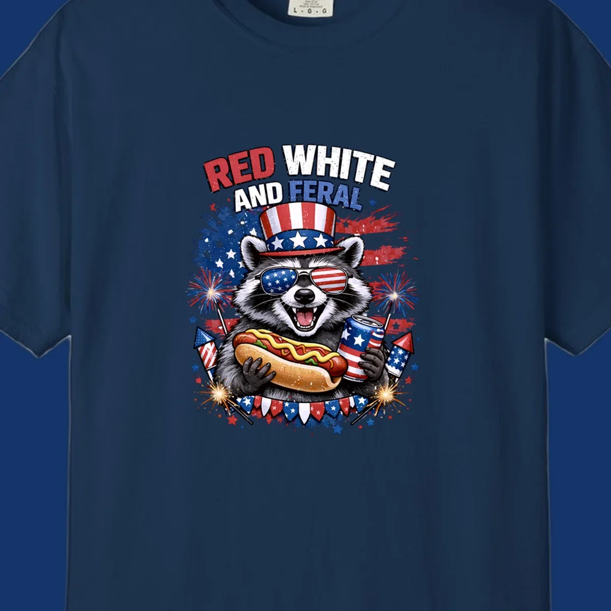 A patriotic raccoon wearing an American flag top hat and sunglasses, holding a hot dog and soda can, with the text 'RED WHITE AND FERAL' and fireworks.