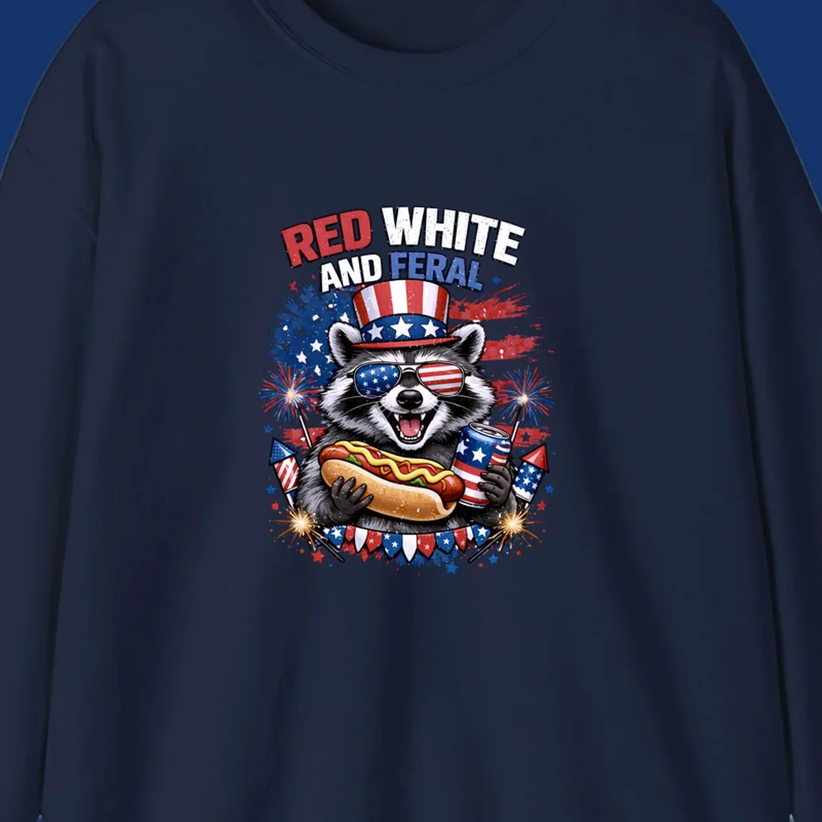 A patriotic raccoon wearing an American flag top hat and sunglasses, holding a hot dog and soda can, with the text 'RED WHITE AND FERAL' and fireworks.