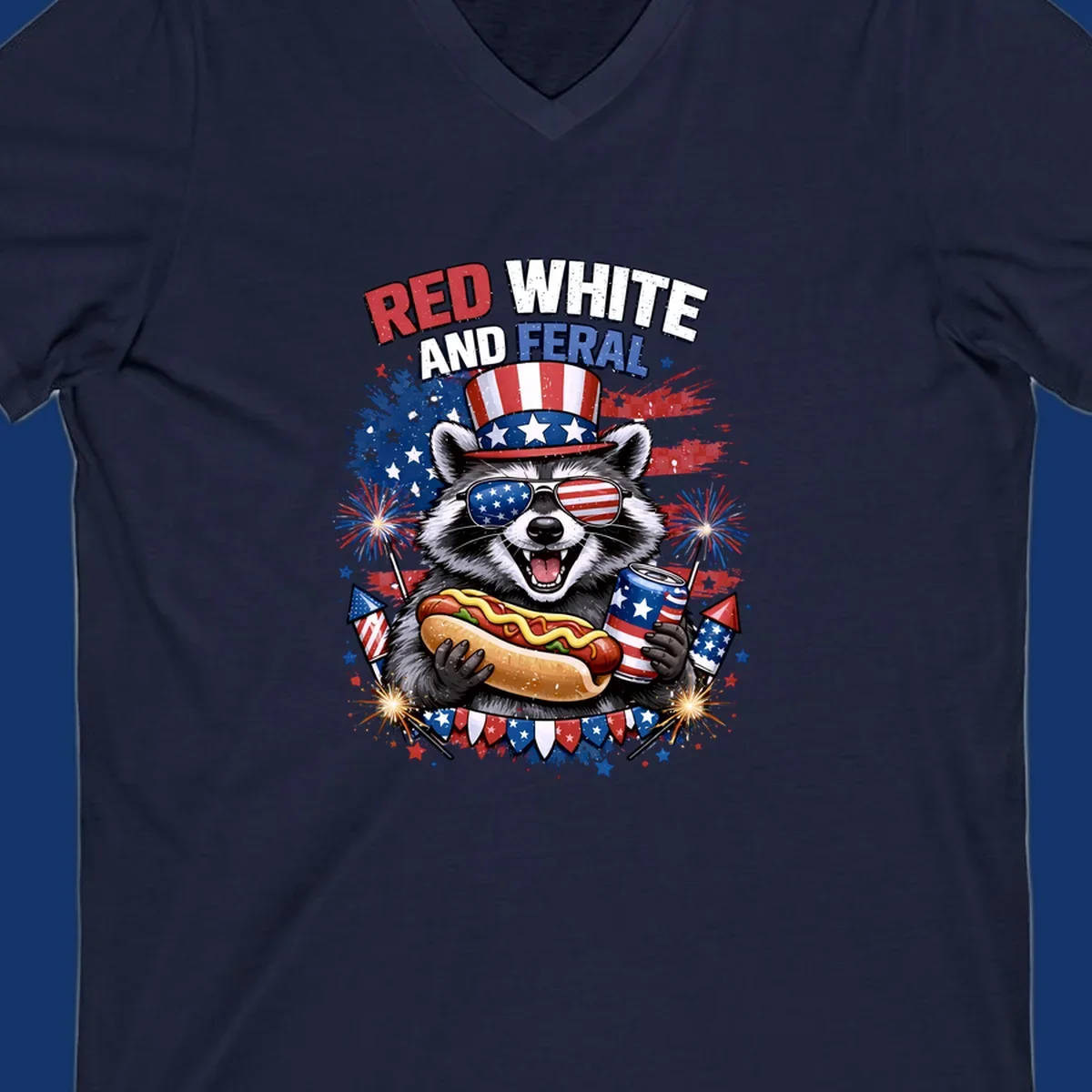 A patriotic raccoon wearing an American flag top hat and sunglasses, holding a hot dog and soda can, with the text 'RED WHITE AND FERAL' and fireworks.