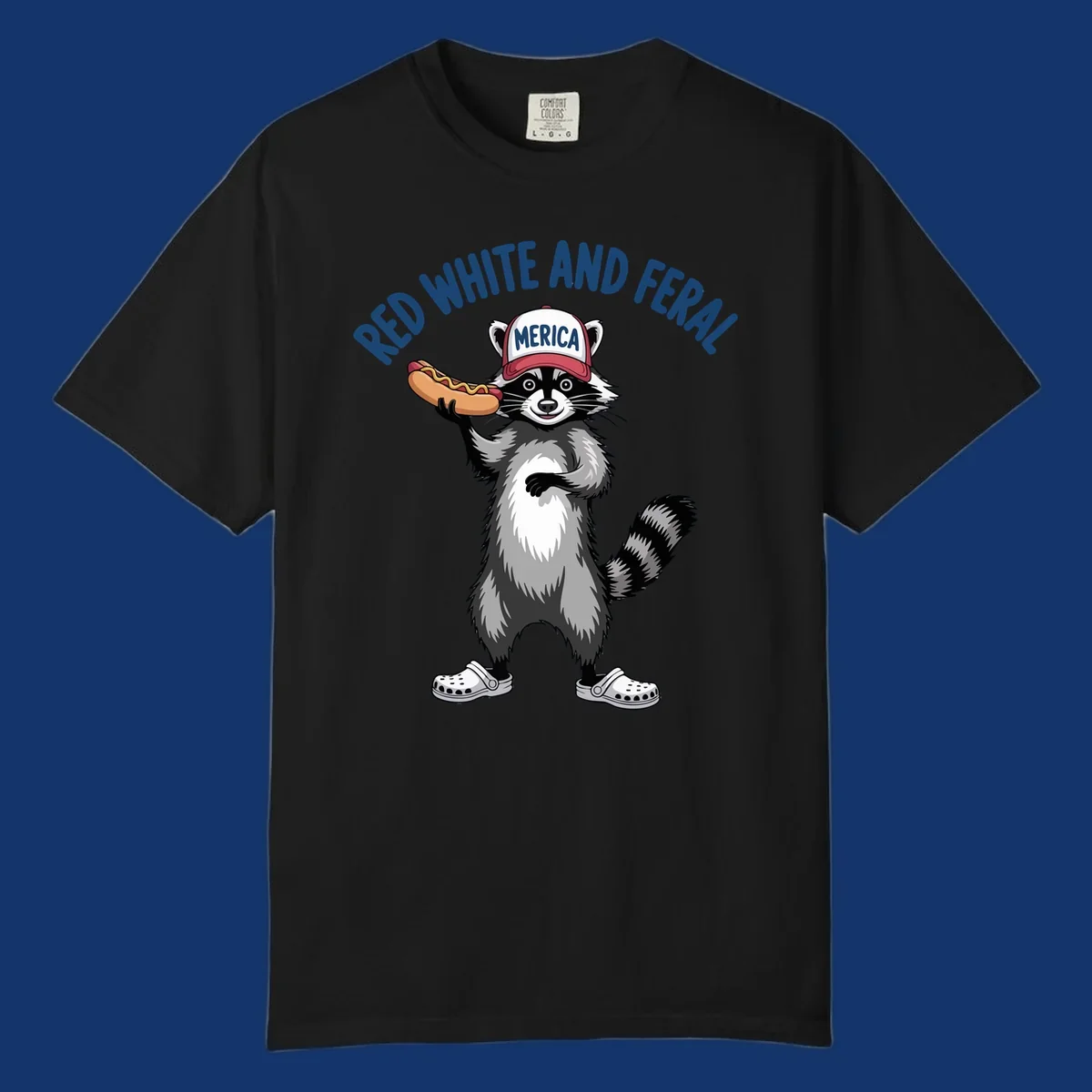 A patriotic raccoon in a MERICA hat and Crocs holds a hot dog, with 'RED WHITE AND FERAL' text. Features the red-white-feral-raccoon concept.