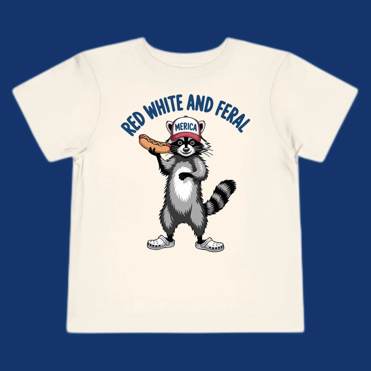 A patriotic raccoon in a MERICA hat and Crocs holds a hot dog, with 'RED WHITE AND FERAL' text. Features the red-white-feral-raccoon concept.