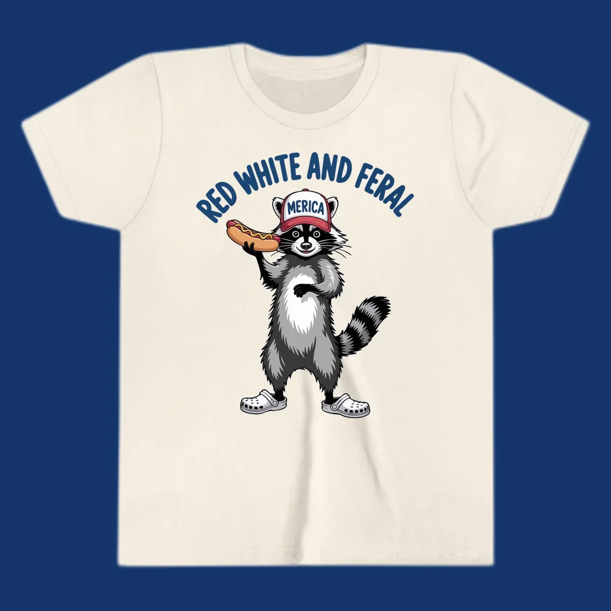 A patriotic raccoon in a MERICA hat and Crocs holds a hot dog, with 'RED WHITE AND FERAL' text. Features the red-white-feral-raccoon concept.