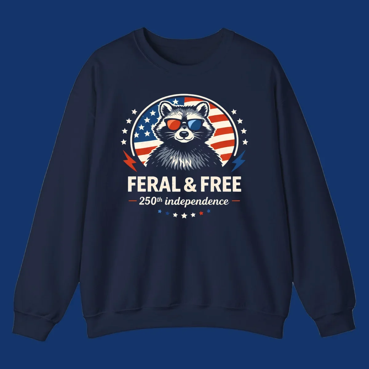 A patriotic design with a raccoon in red and blue sunglasses against an American flag, with text 'Feral & Free 250th Independence'.