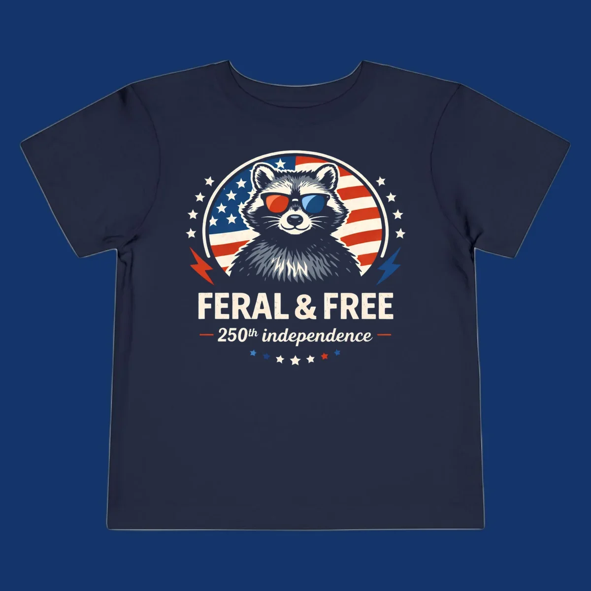 A patriotic design with a raccoon in red and blue sunglasses against an American flag, with text 'Feral & Free 250th Independence'.