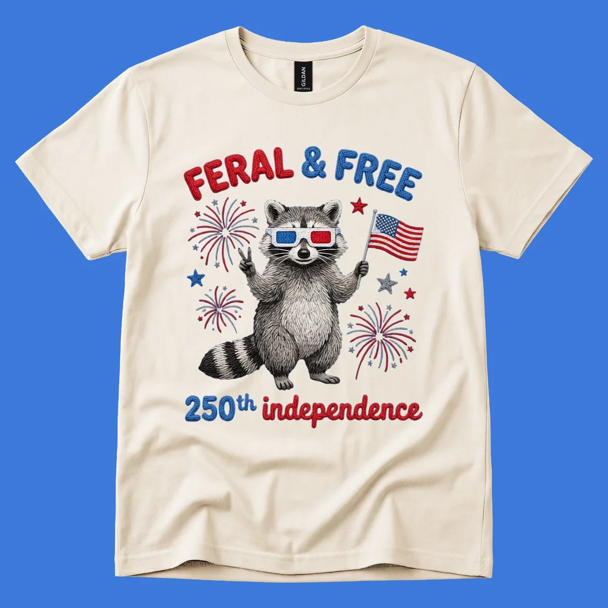 A playful raccoon in 3D glasses holds an American flag, surrounded by fireworks and stars, with "FERAL & FREE 250th independence".