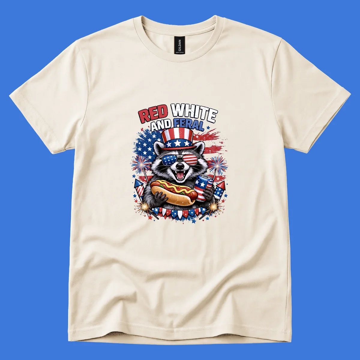 A patriotic raccoon wearing an American flag top hat and sunglasses, holding a hot dog and soda can, with the text 'RED WHITE AND FERAL' and fireworks.