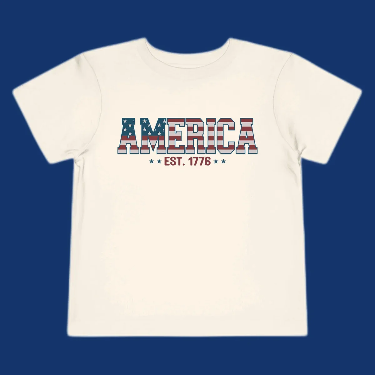The word AMERICA in block letters, filled with an American flag pattern, above the text EST. 1776 with stars. Concept: america-est-1776-flag.