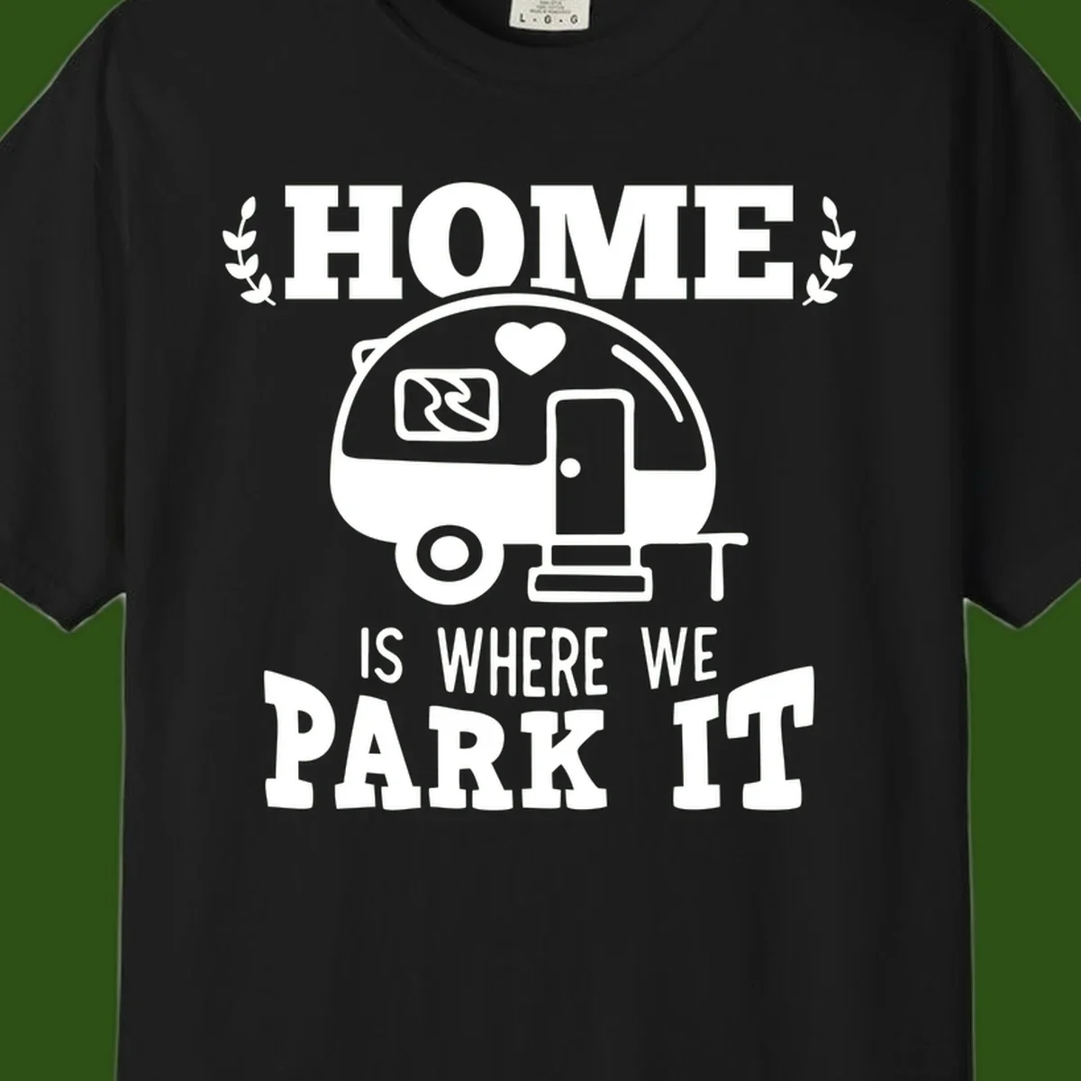 Vintage travel trailer illustration with 'Home Is Where We Park It' text and laurel wreaths on gray background