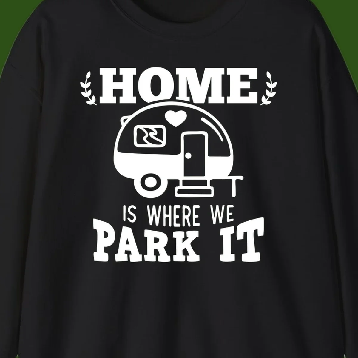 Vintage travel trailer illustration with 'Home Is Where We Park It' text and laurel wreaths on gray background