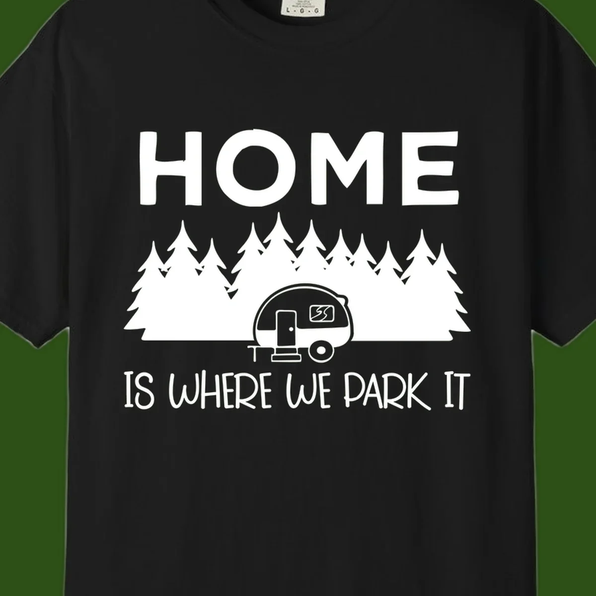Home is where we park it design with travel trailer and forest trees on gray background