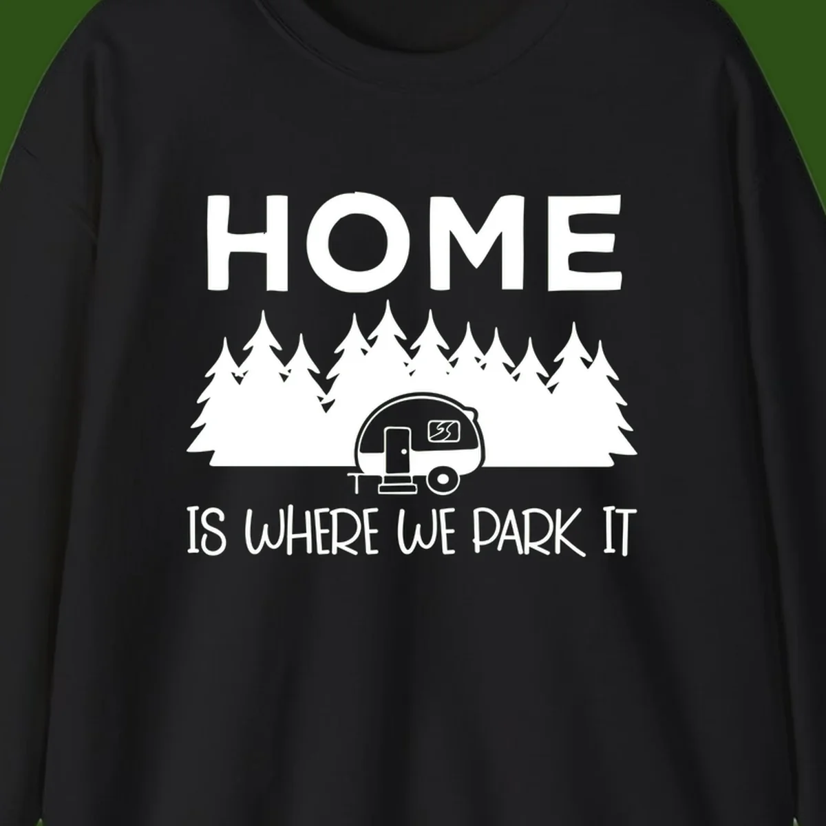Home is where we park it design with travel trailer and forest trees on gray background