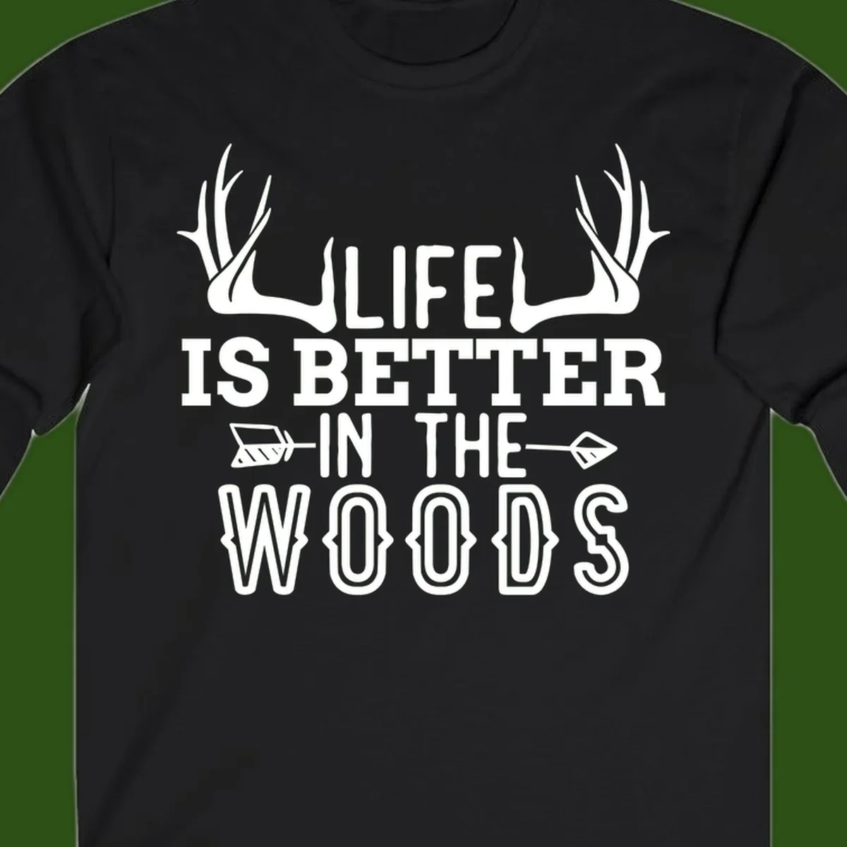 White text reading 'Life Is Better In The Woods' with deer antlers and arrows on gray background