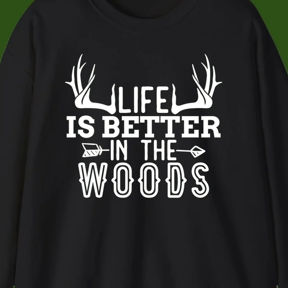 White text reading 'Life Is Better In The Woods' with deer antlers and arrows on gray background