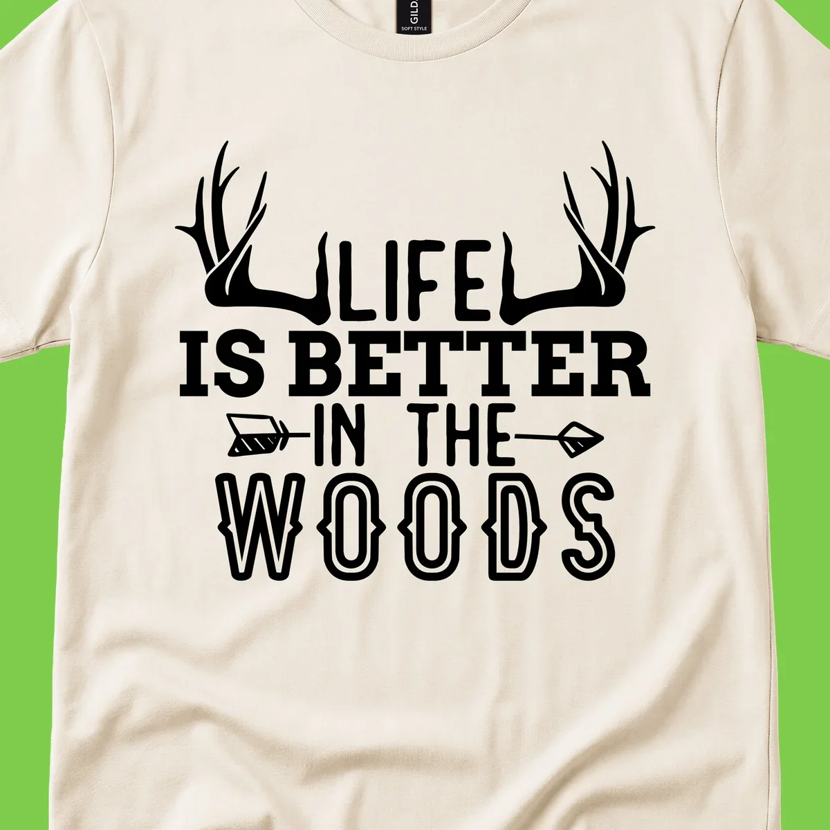 White text reading 'Life Is Better In The Woods' with deer antlers and arrows on gray background
