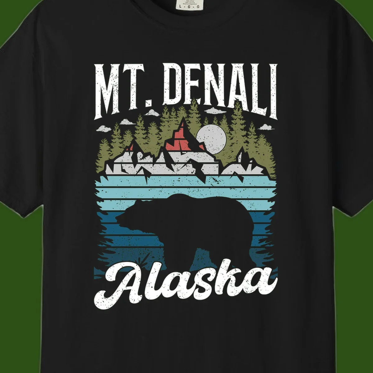 Denali bear Alaska design: layered illustration with silhouetted bear emerging from water, mountain peaks, fortress, forest, and full moon.