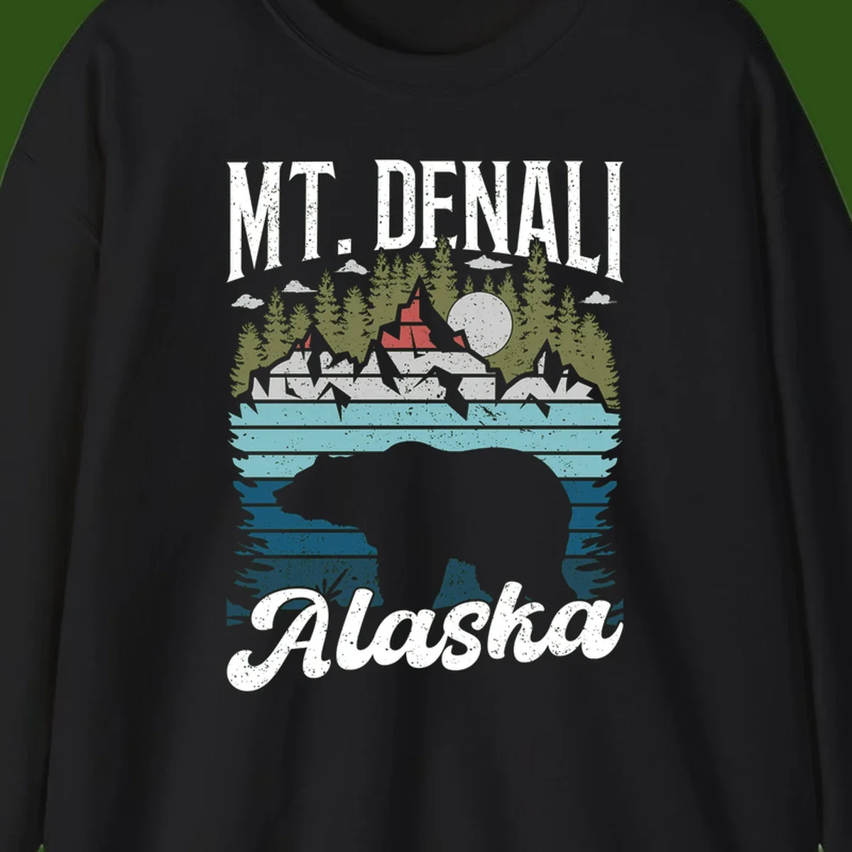 Denali bear Alaska design: layered illustration with silhouetted bear emerging from water, mountain peaks, fortress, forest, and full moon.