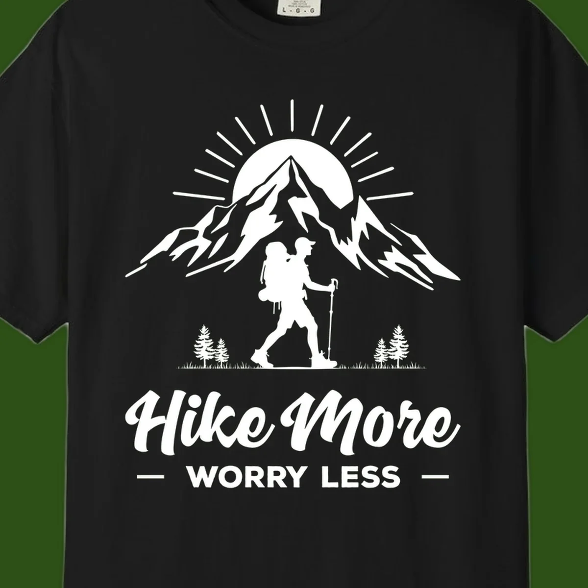 Silhouette of hiker with backpack and poles facing snow-capped mountain with radiating sun, evergreen trees below, text reads 'Hike More Worry Less'