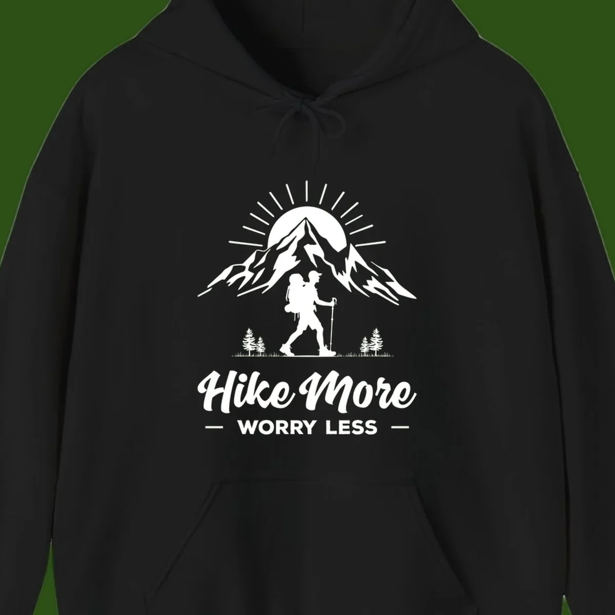 Silhouette of hiker with backpack and poles facing snow-capped mountain with radiating sun, evergreen trees below, text reads 'Hike More Worry Less'