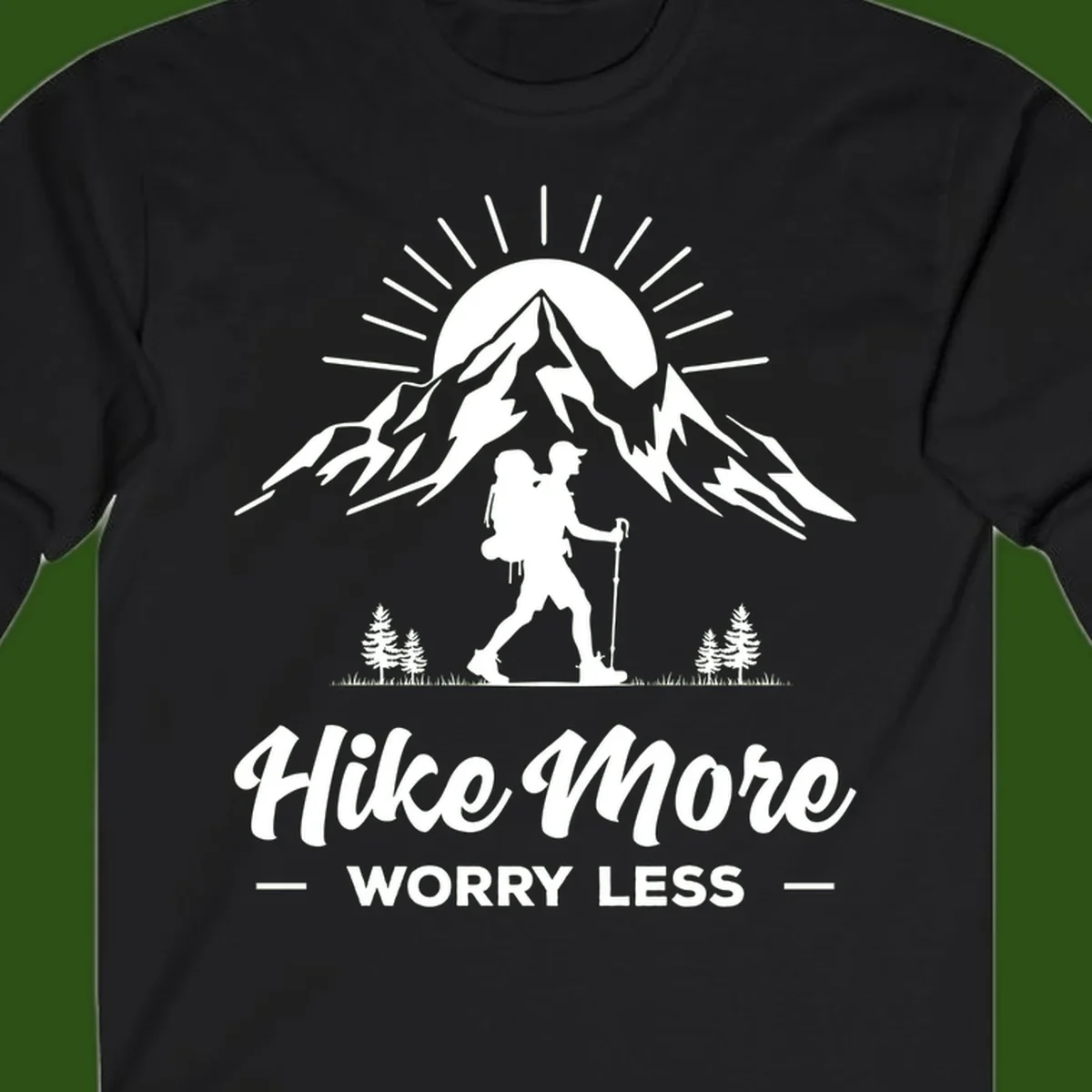 Silhouette of hiker with backpack and poles facing snow-capped mountain with radiating sun, evergreen trees below, text reads 'Hike More Worry Less'