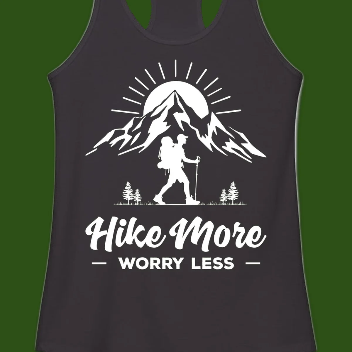 Silhouette of hiker with backpack and poles facing snow-capped mountain with radiating sun, evergreen trees below, text reads 'Hike More Worry Less'