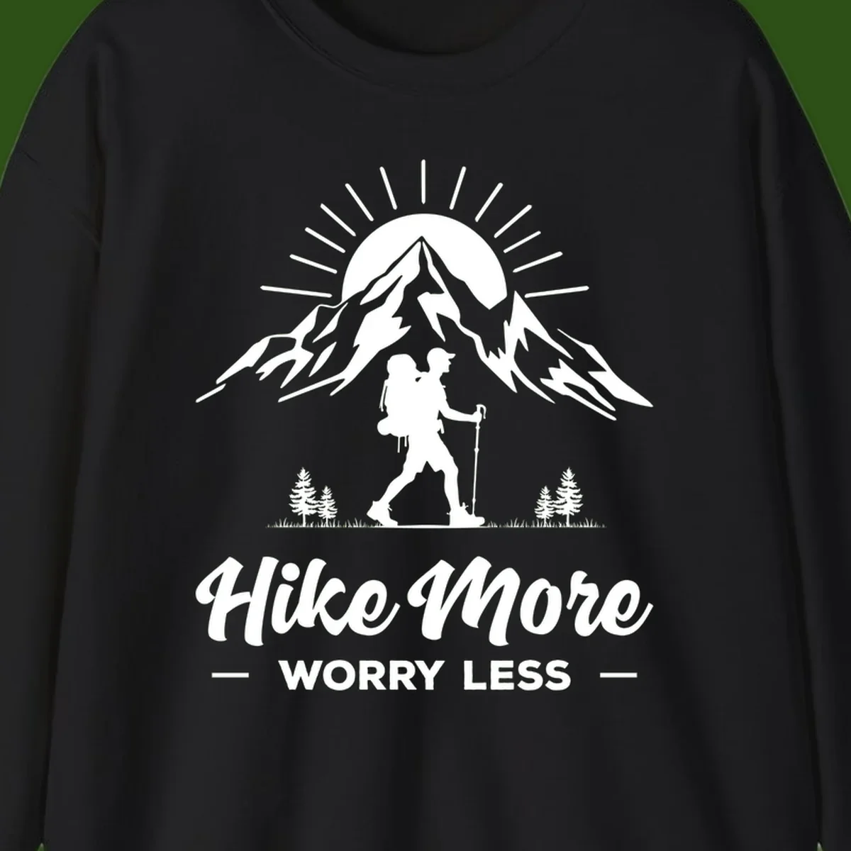 Silhouette of hiker with backpack and poles facing snow-capped mountain with radiating sun, evergreen trees below, text reads 'Hike More Worry Less'