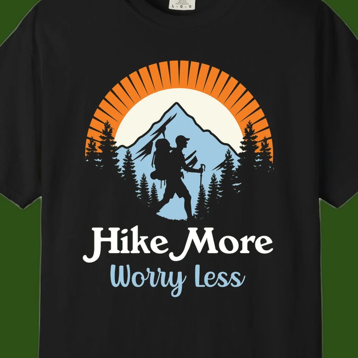 Hike more worry less badge design with silhouetted hiker, mountain peak, and evergreen forest in circular composition.