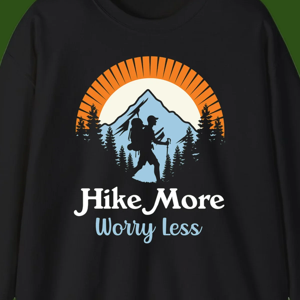 Hike more worry less badge design with silhouetted hiker, mountain peak, and evergreen forest in circular composition.
