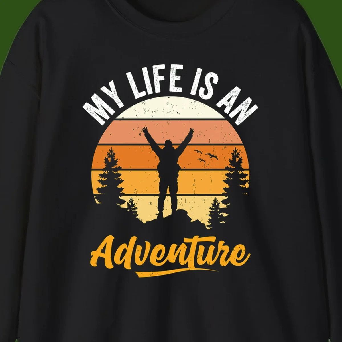 Retro sunset illustration with silhouette of person celebrating arms raised, evergreen trees and mountains, text 'My Life Is An Adventure'