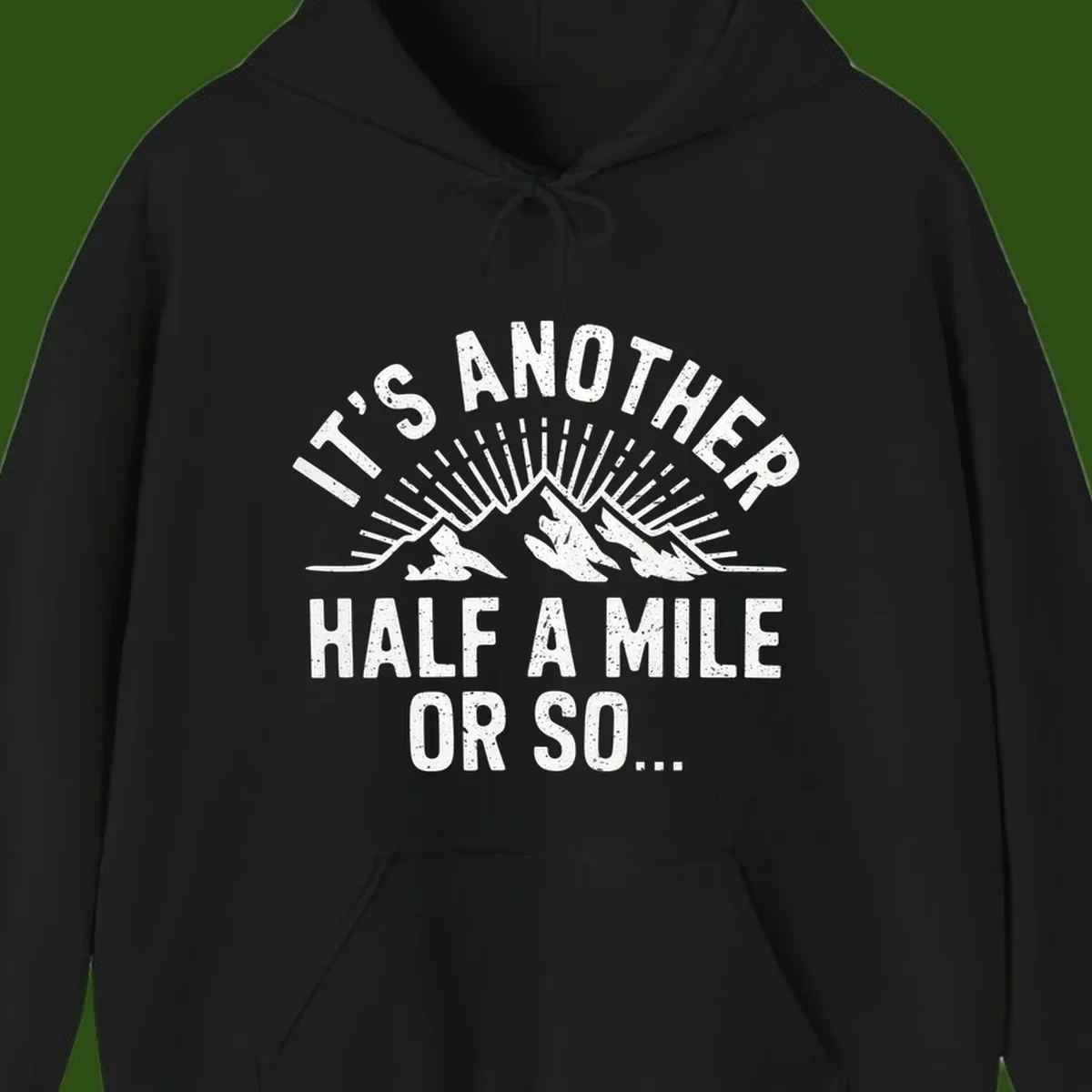 Retro distressed design with mountain peaks and sun rays, text reads 'It's Another Half A Mile Or So' - humorous hiking and camping artwork