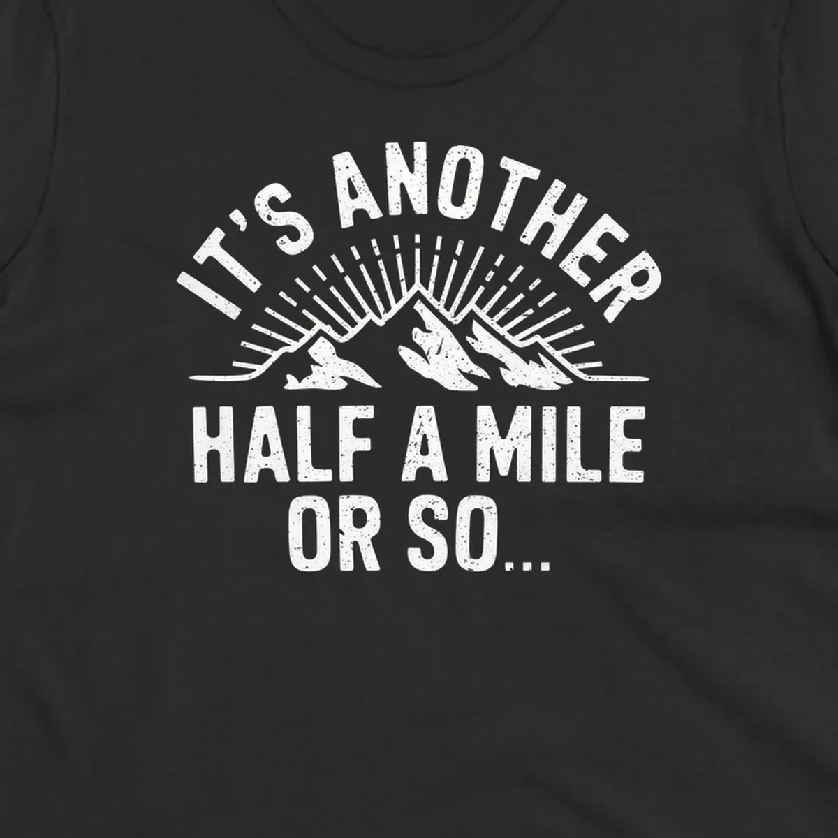 Retro distressed design with mountain peaks and sun rays, text reads 'It's Another Half A Mile Or So' - humorous hiking and camping artwork