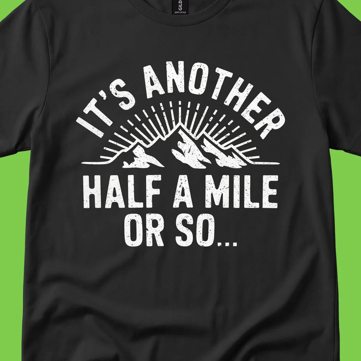 Retro distressed design with mountain peaks and sun rays, text reads 'It's Another Half A Mile Or So' - humorous hiking and camping artwork