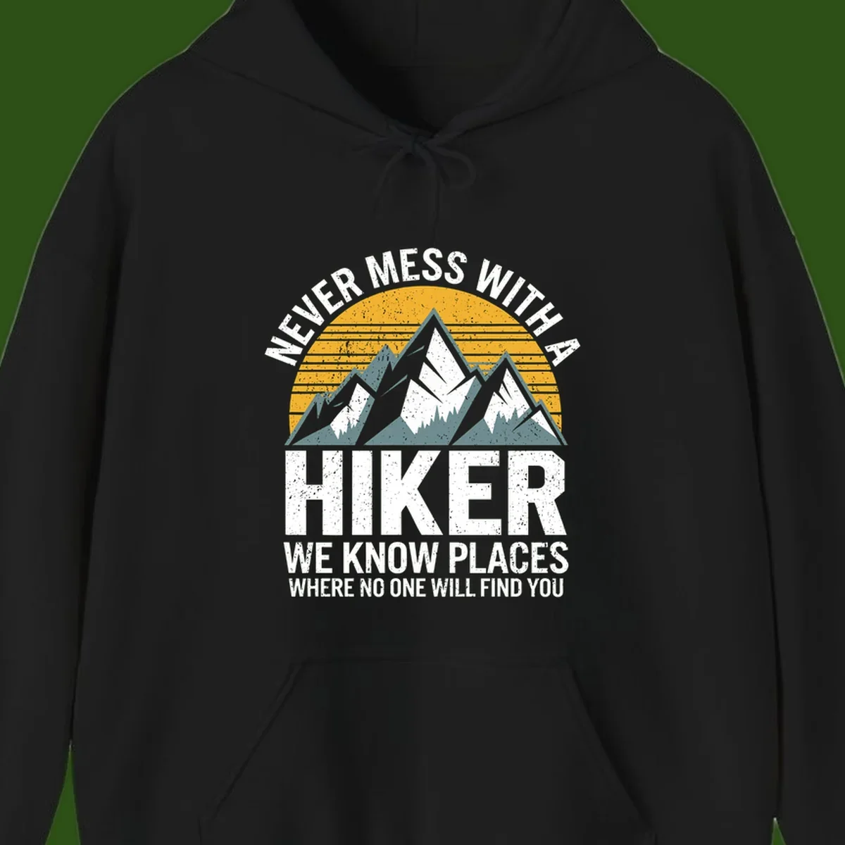 Vintage-style design with snow-capped mountains and forest silhouette against striped sunset, text reads 'Never Mess With A Hiker We Know Places Where No One Will Find You'