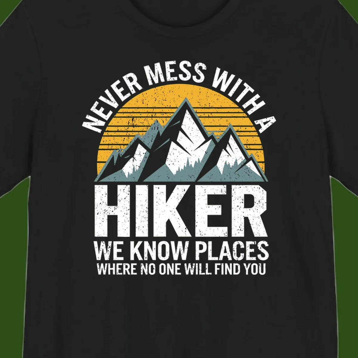 Vintage-style design with snow-capped mountains and forest silhouette against striped sunset, text reads 'Never Mess With A Hiker We Know Places Where No One Will Find You'