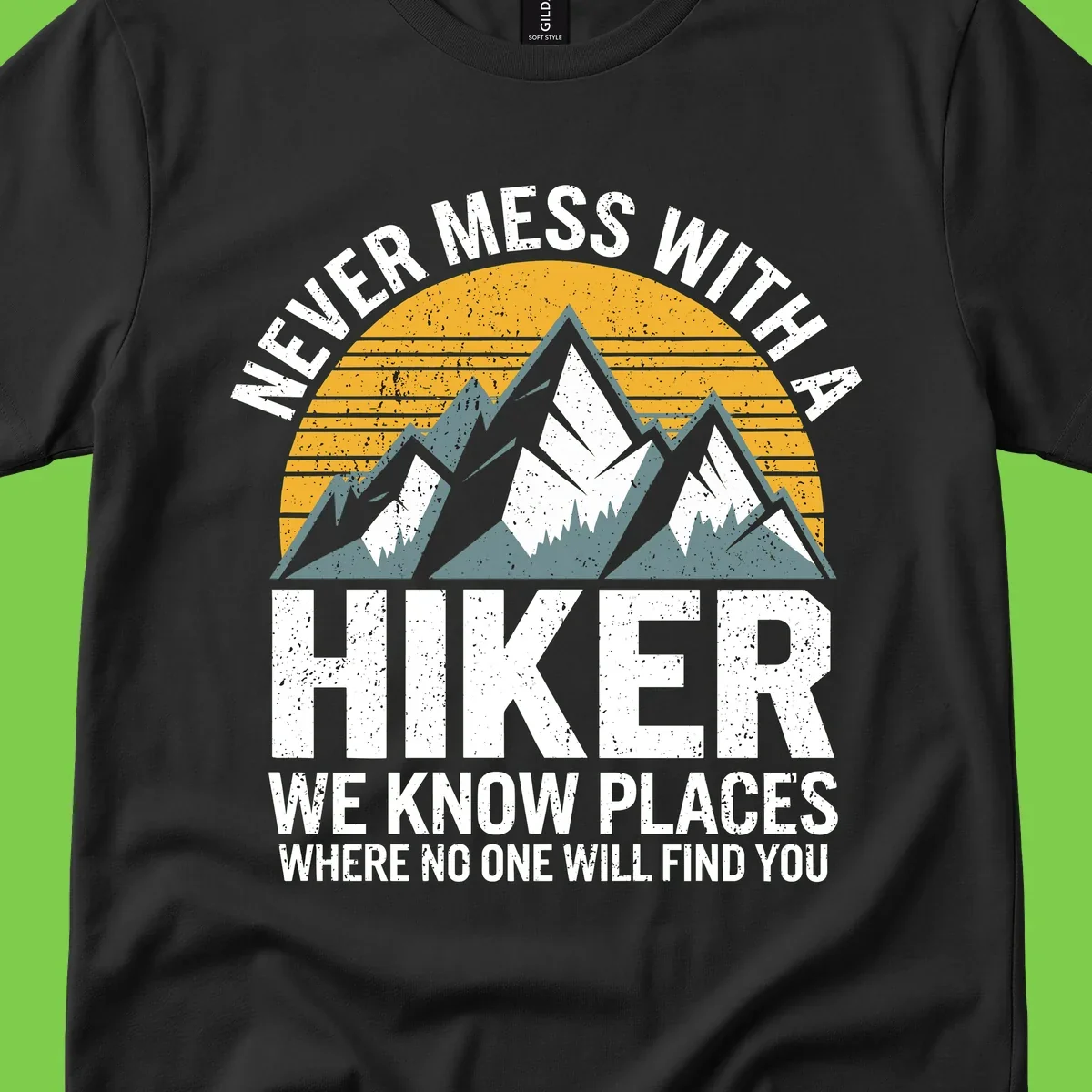 Vintage-style design with snow-capped mountains and forest silhouette against striped sunset, text reads 'Never Mess With A Hiker We Know Places Where No One Will Find You'