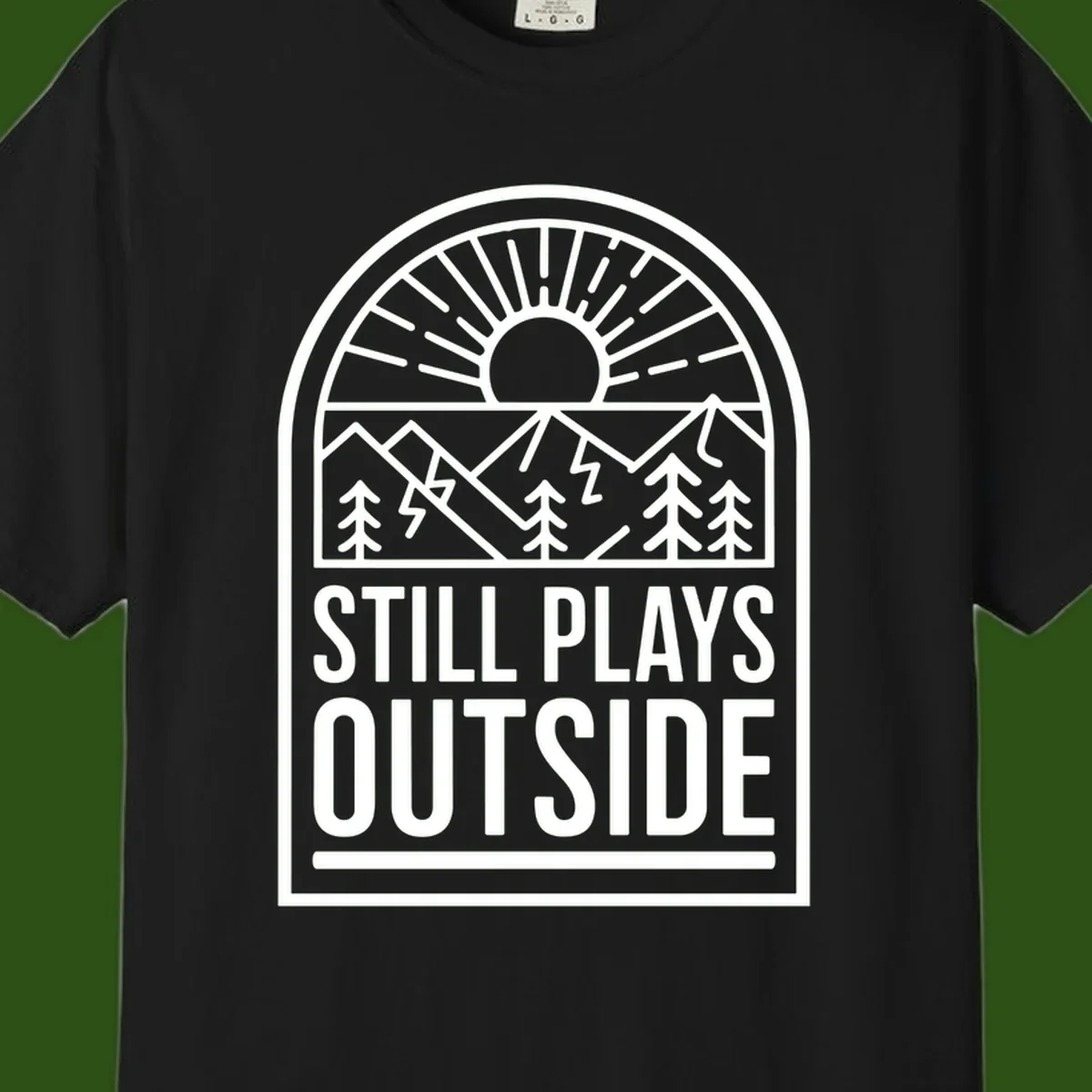 Still Plays Outside badge design featuring mountains, sun, pine trees, and lightning bolt in minimalist line art style