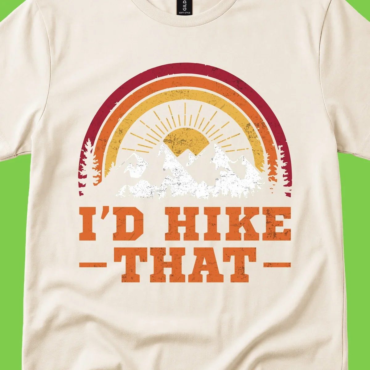 Vintage badge design with snow-capped mountains, evergreen trees, golden sun rays, and text reading 'I'd Hike That' in retro style