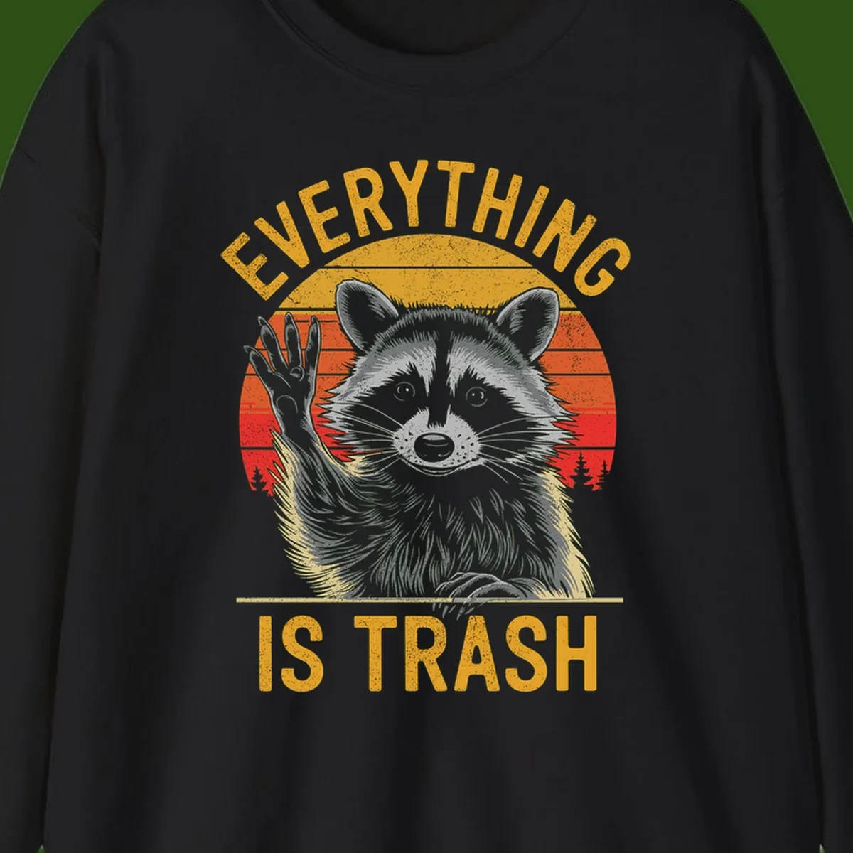 Vintage-style illustration of a raccoon with raised paw against retro sunset stripes, text reading 'Everything Is Trash' in distressed gold lettering