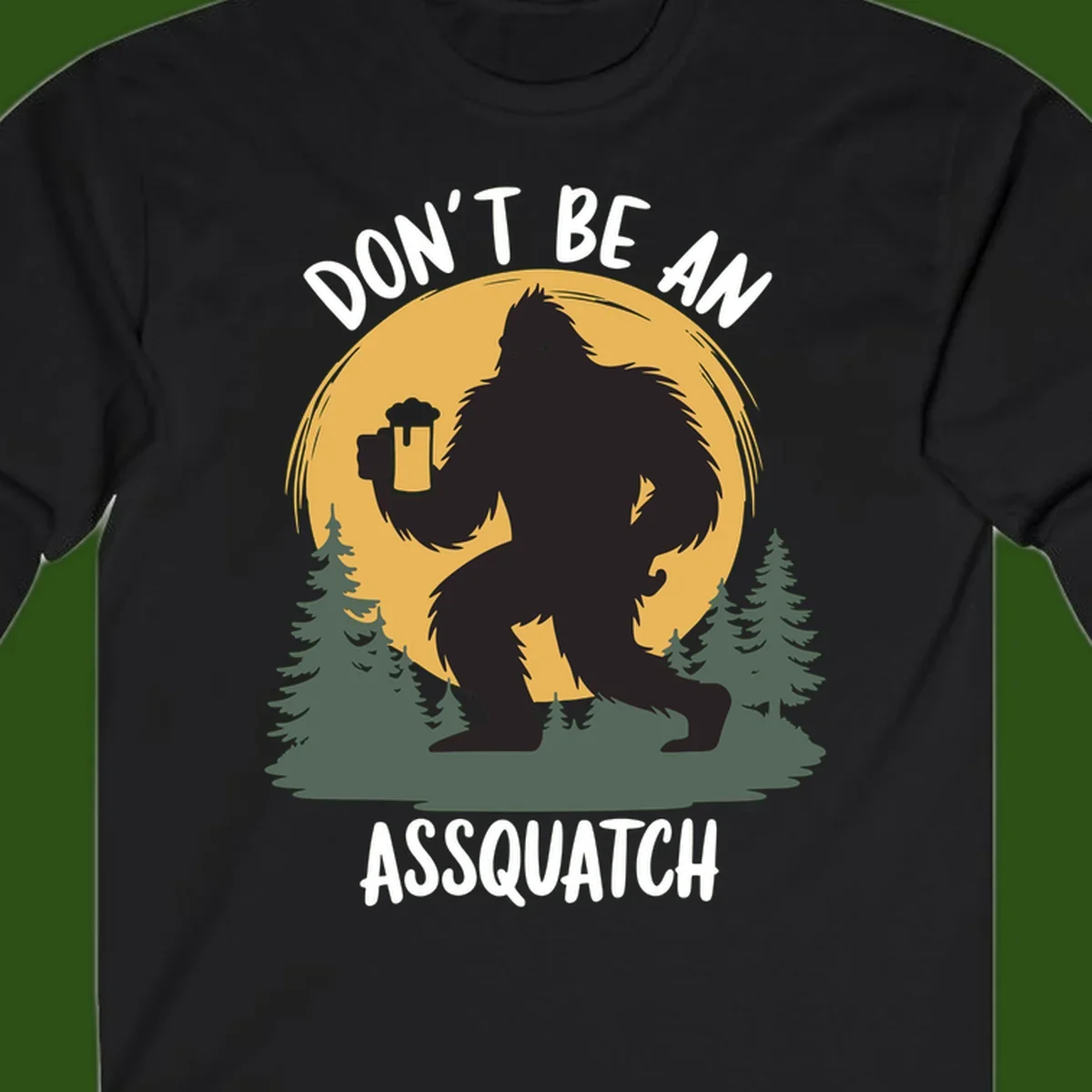 Black silhouette of Bigfoot holding a beer mug under a full moon with pine trees, text reads don't be an assquatch