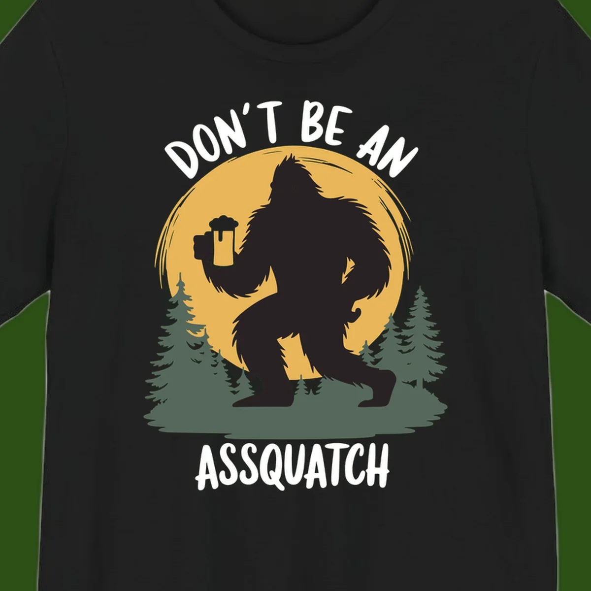 Black silhouette of Bigfoot holding a beer mug under a full moon with pine trees, text reads don't be an assquatch
