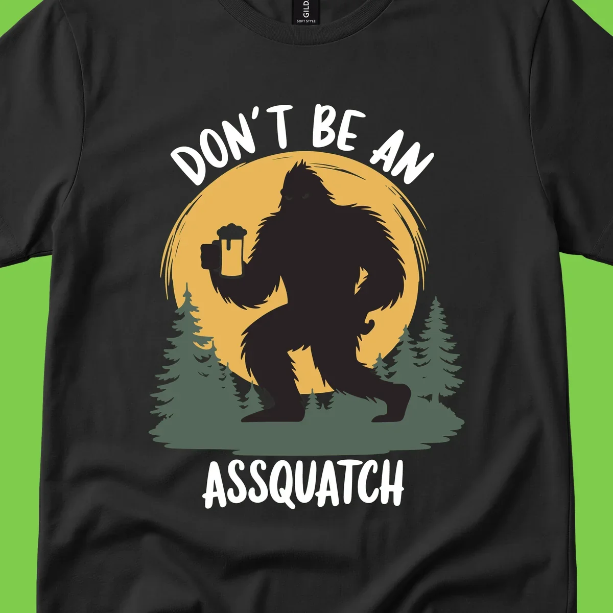 Black silhouette of Bigfoot holding a beer mug under a full moon with pine trees, text reads don't be an assquatch