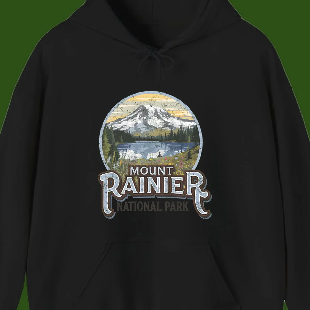 Vintage Mount Rainier National Park badge design with snow-capped peak, alpine lake, evergreen forest, and wildflowers on distressed background