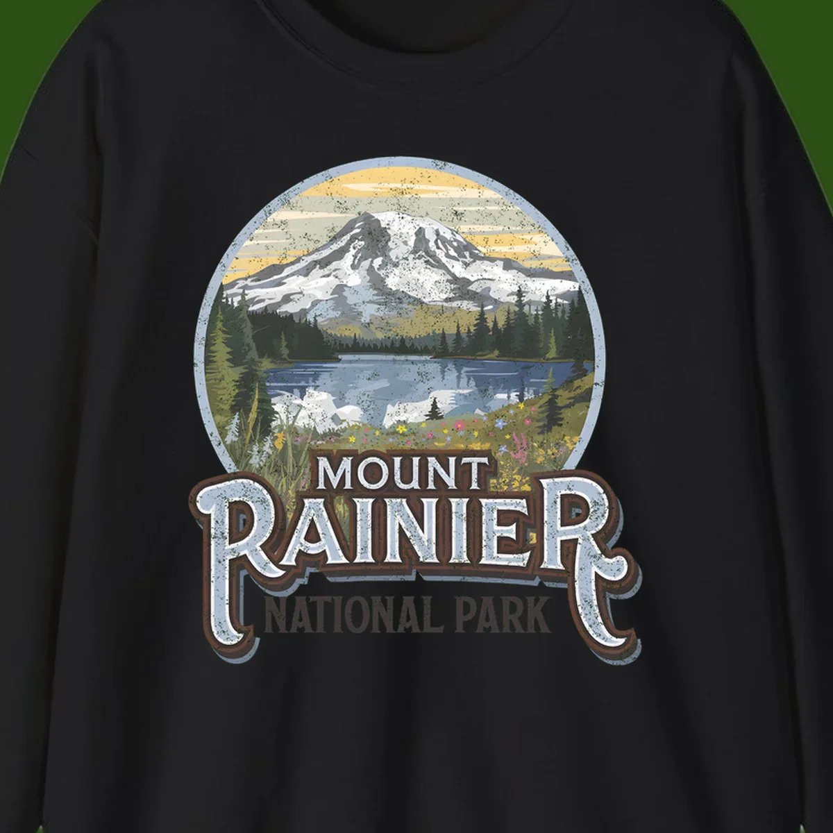 Vintage Mount Rainier National Park badge design with snow-capped peak, alpine lake, evergreen forest, and wildflowers on distressed background