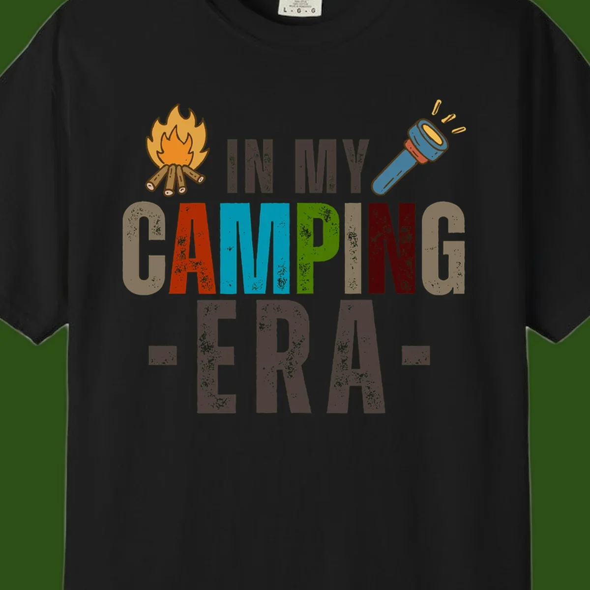 Campfire and flashlight icons flank colorful distressed text reading 'In My Camping Era' on gray background