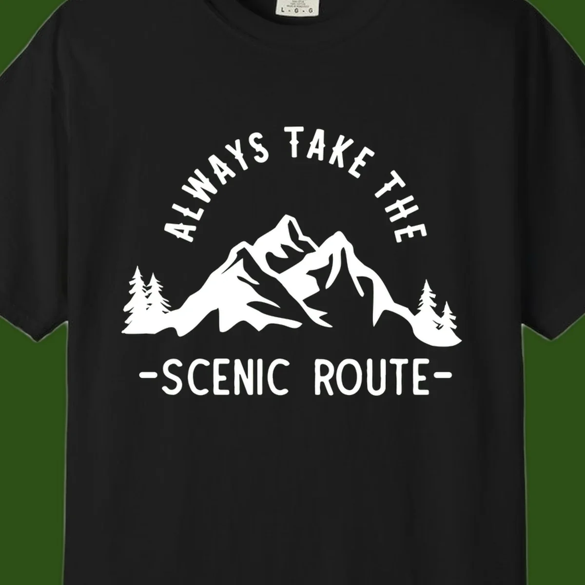 Mountain landscape with evergreen trees and text reading 'Always Take The Scenic Route' in bold lettering
