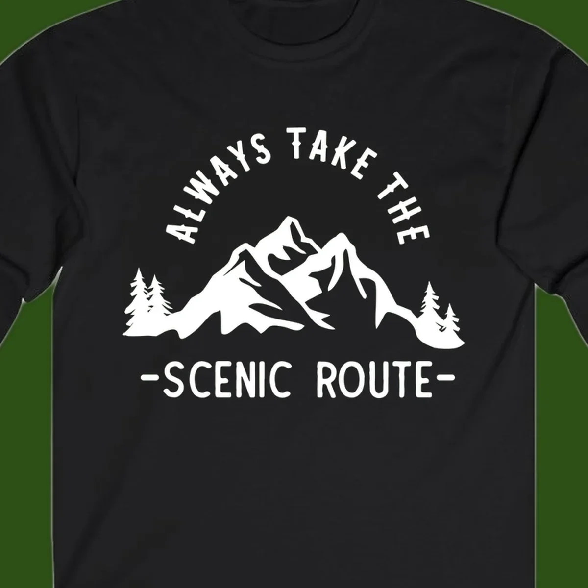 Mountain landscape with evergreen trees and text reading 'Always Take The Scenic Route' in bold lettering